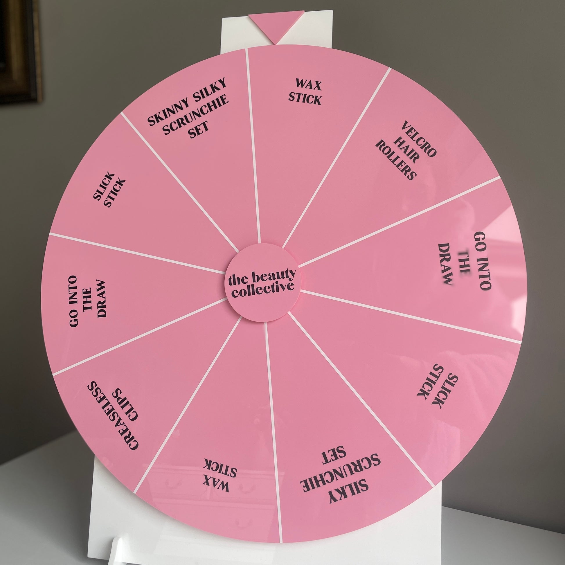 custom pink branded spinning prize wheel for a business event with custom vinyl prizes in the sections of the laser cut spinning wheel