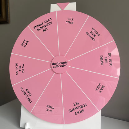 custom pink branded spinning prize wheel for a business event with custom vinyl prizes in the sections of the laser cut spinning wheel